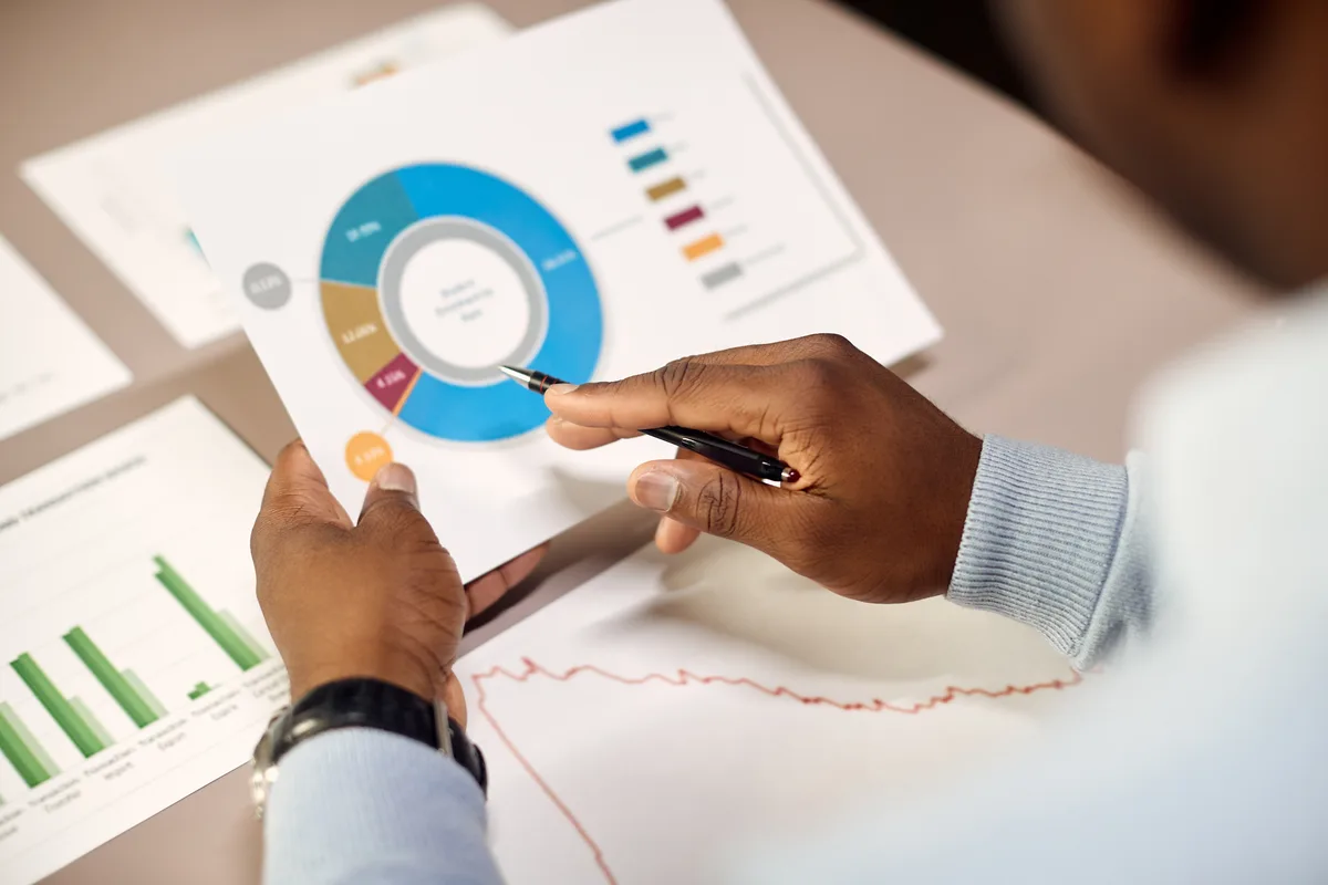 Hands annotating a printed breakdown chart alongside other analysis outputs